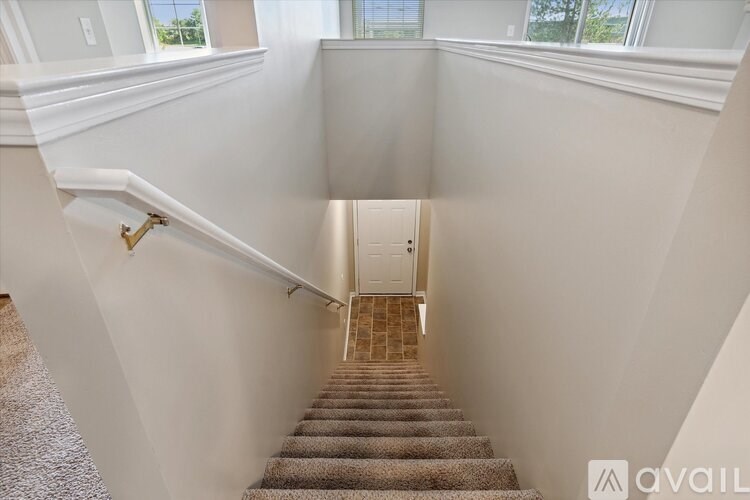 A staircase with a carpeted runner and a brass handrail.