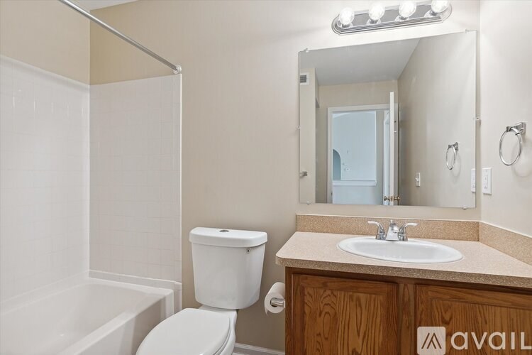 A bathroom with a toilet, sink, and mirror.