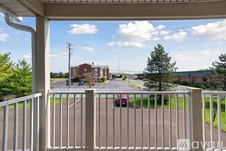 A view from a balcony looking out at a street with cars and buildings.