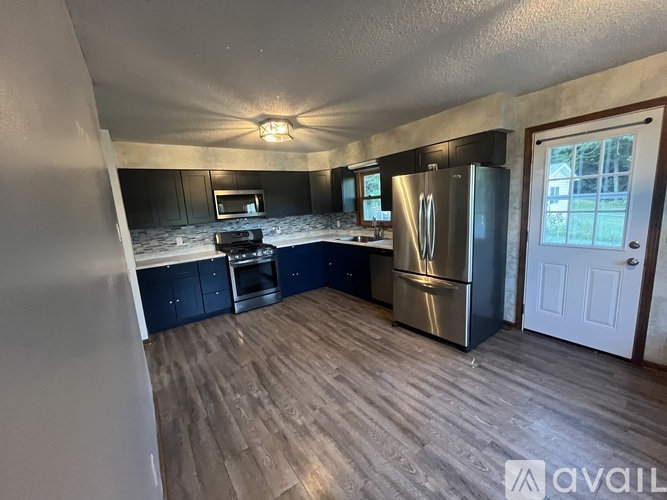 A kitchen with dark blue cabinets and a stainless steel refrigerator.