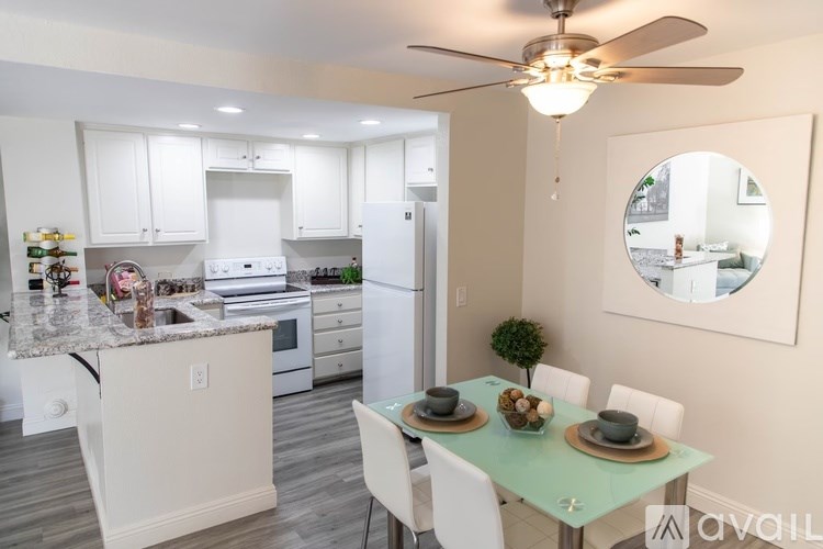 A kitchen with a table set for two and a ceiling fan.