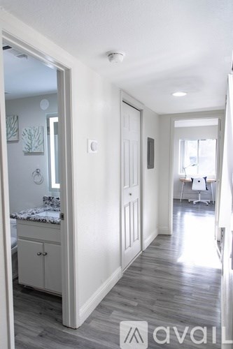 A hallway with a white door and a white cabinet with a mirror above it.