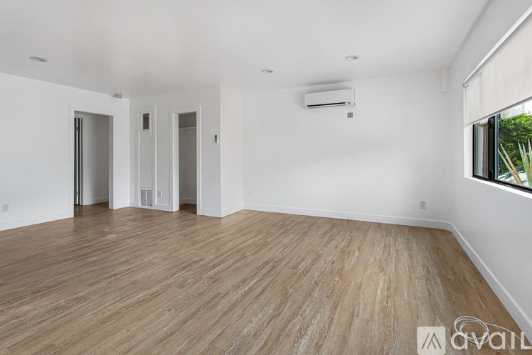 A spacious room with wooden flooring and white walls.
