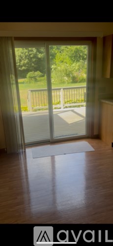 A room with a wooden floor and a large window with a view of a green lawn.