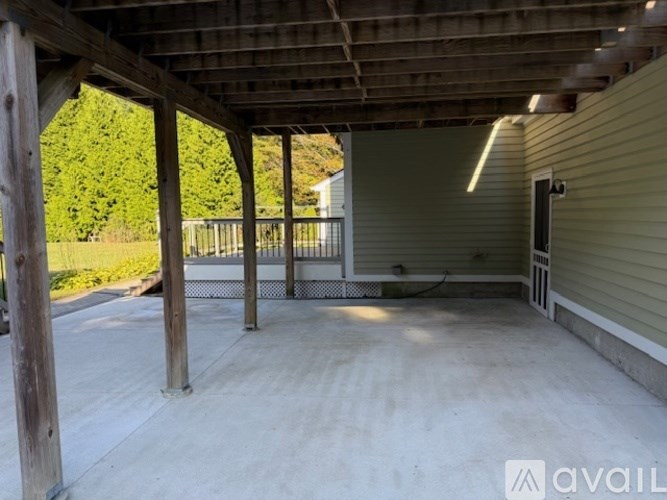 A covered patio area with a concrete floor and wooden pillars.