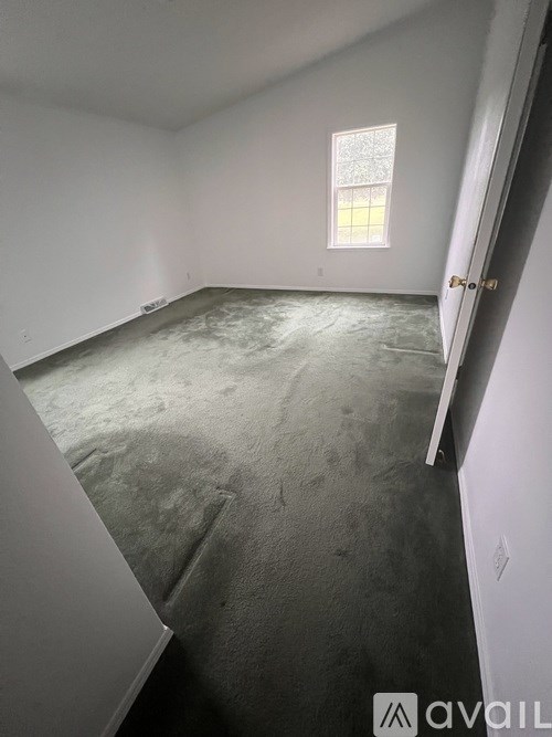 A room with a window and a carpeted floor.