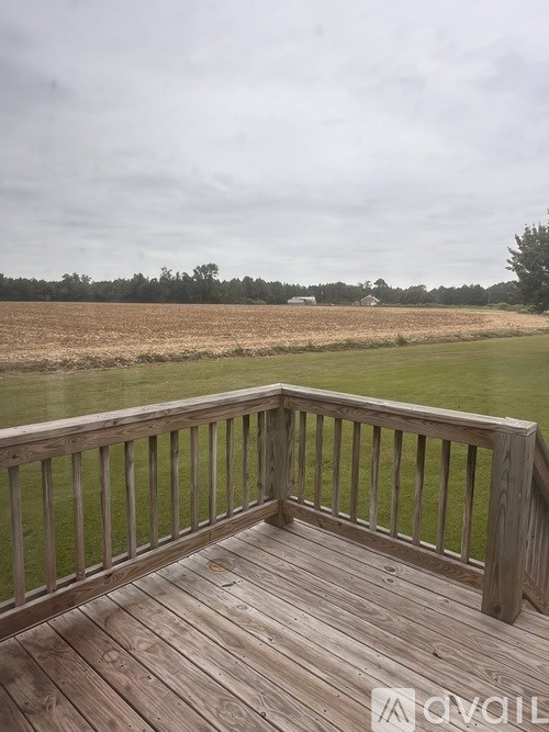 A wooden deck overlooks a field.