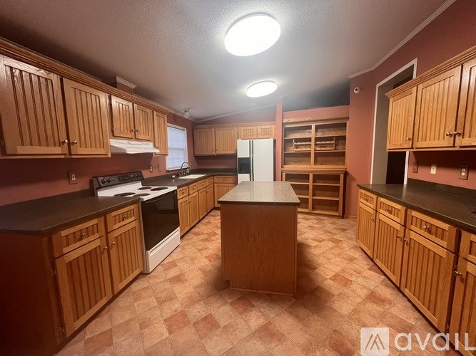 A house with a porch and a deck is surrounded by grass and trees.
