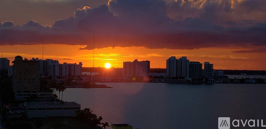 A sunset over a city with buildings and a body of water.