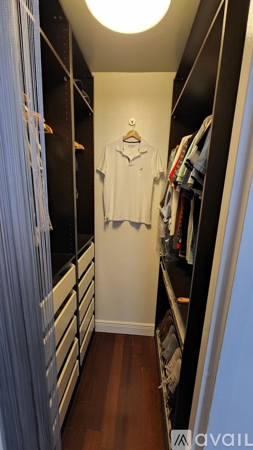 A white shirt hanging on a hanger in a dark closet.