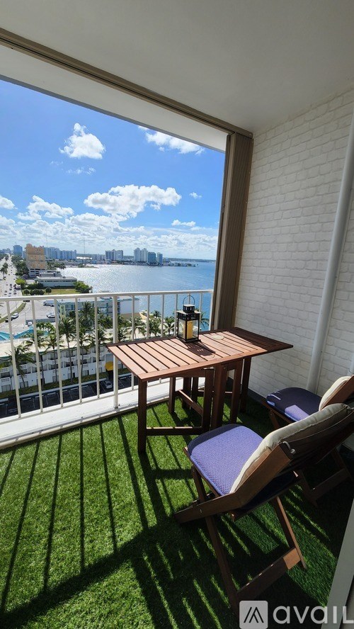 A balcony with a table and chairs overlooking a cityscape.