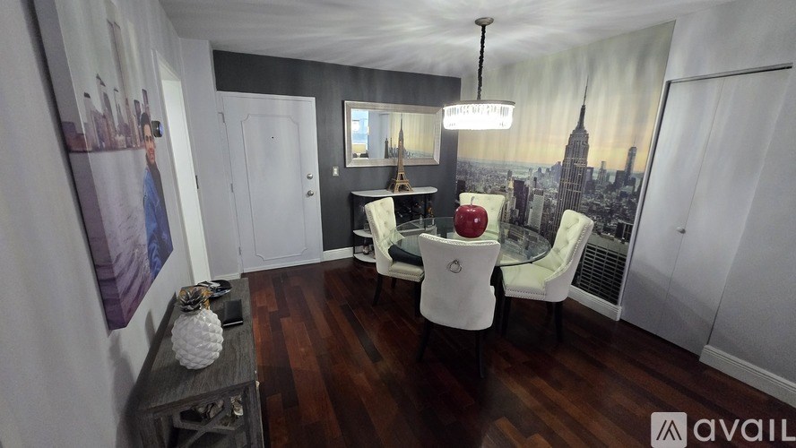 A room with a wooden floor and a large window with a view of a city skyline.