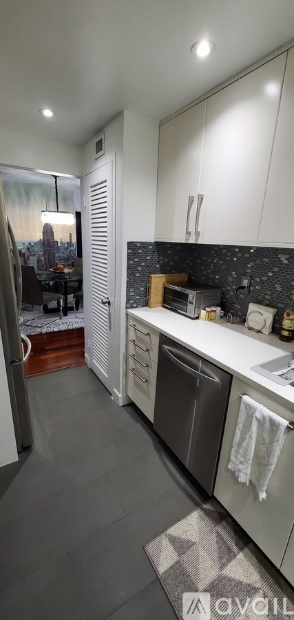 A kitchen with white cabinets and a grey floor.