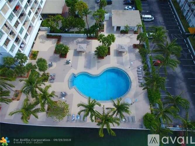 A swimming pool surrounded by palm trees and a building in the background.
