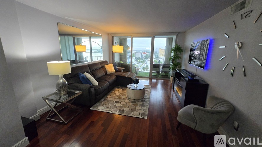 A living room with a couch, a chair, a table, and a large clock on the wall.