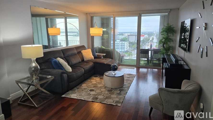 A living room with a couch, a chair, a coffee table, and a large window with a view of the city.