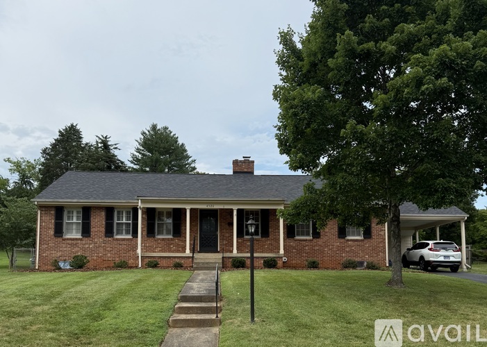 A brick house with a black door and a tree in front.