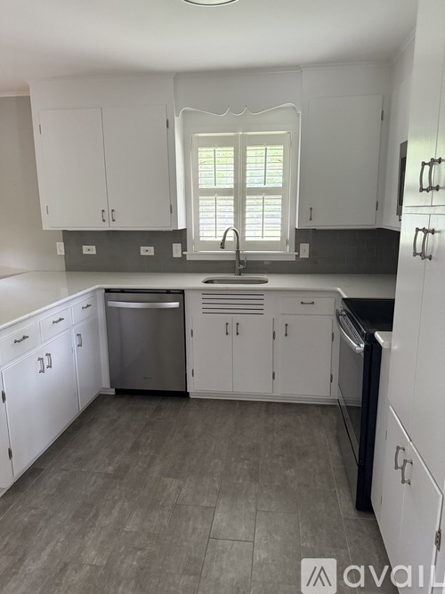 A kitchen with white cabinets and a window above the sink.