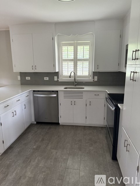 A kitchen with white cabinets and a window above the sink.