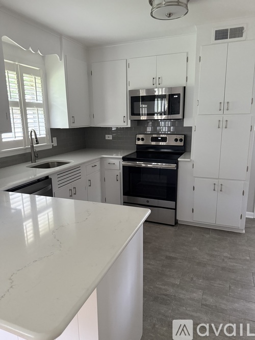 A kitchen with white cabinets and a marble countertop.