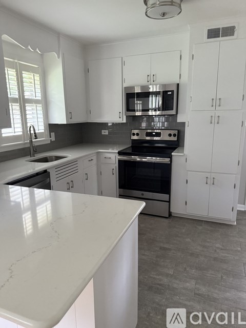 A kitchen with white cabinets and a marble countertop.