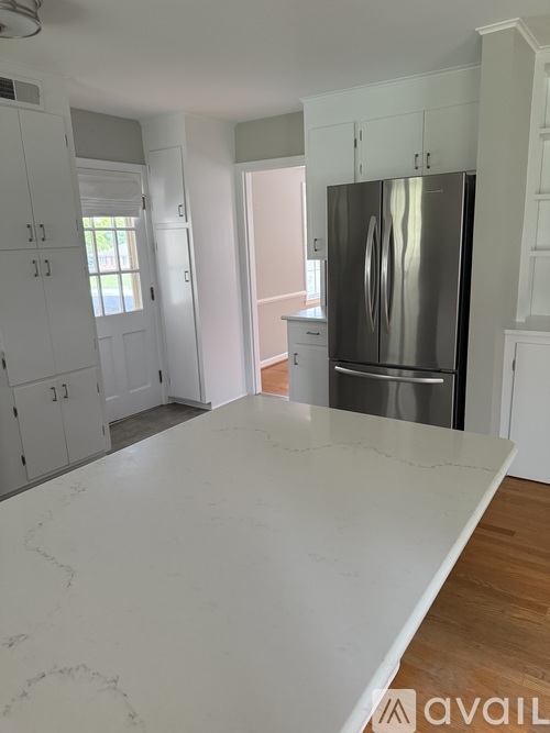 A kitchen with a marble countertop and a stainless steel refrigerator.