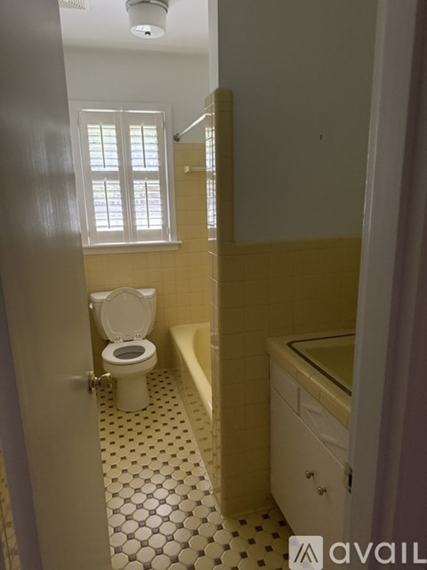 A bathroom with a toilet, sink, and a window.