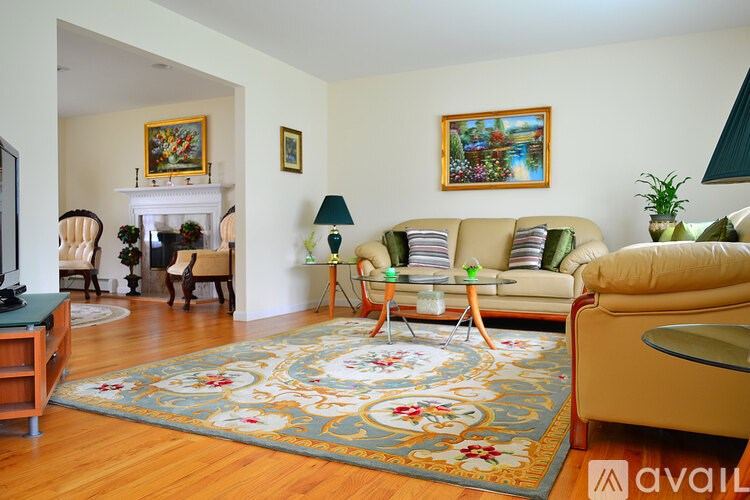 A living room with a rug, couch, and chairs.