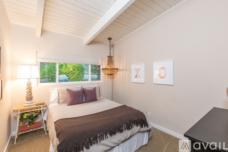 A bedroom with a large bed and a window overlooking a green area.