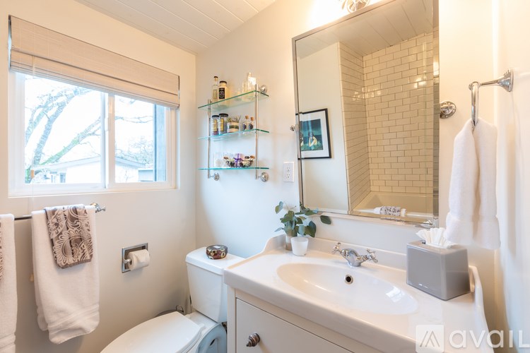 A bathroom with a white toilet, sink, and a window.