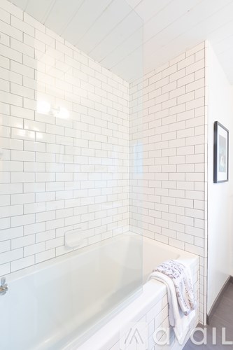 A white bathroom with a white tub and a white tiled wall.