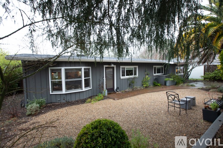 A grey house with a patio and trees in the background.