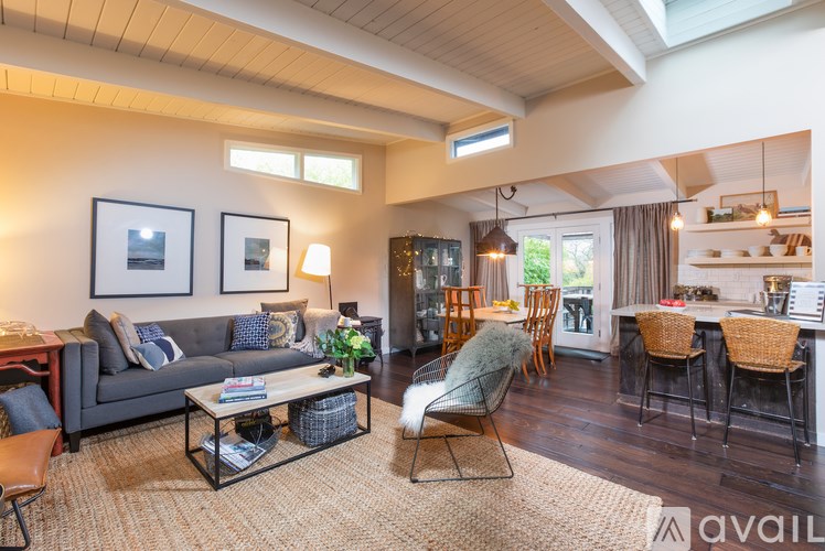 A living room with a grey couch, a coffee table, and a dining table with chairs.