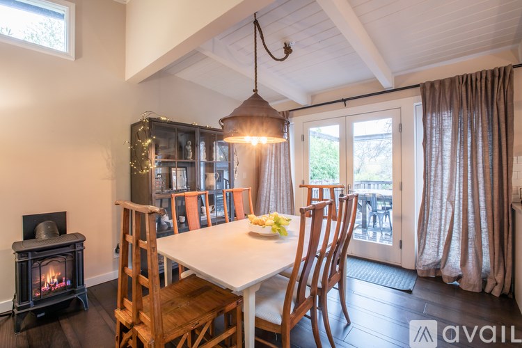 A dining room with a white table and chairs, a fireplace, and a view of the backyard through the sliding glass doors.
