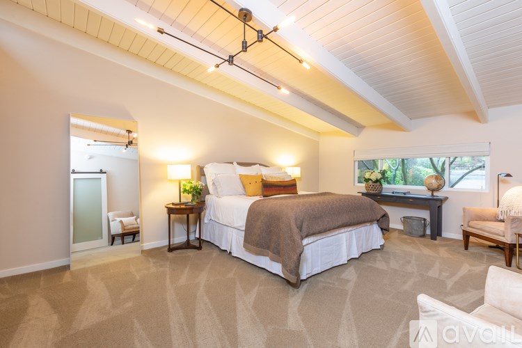 A bedroom with a large bed and a window overlooking trees.
