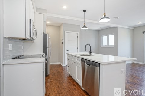 A kitchen with white cabinets and a wooden floor.