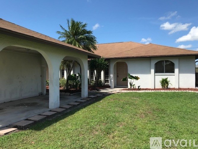 A house with a white exterior and a brown roof with a lawn in front.