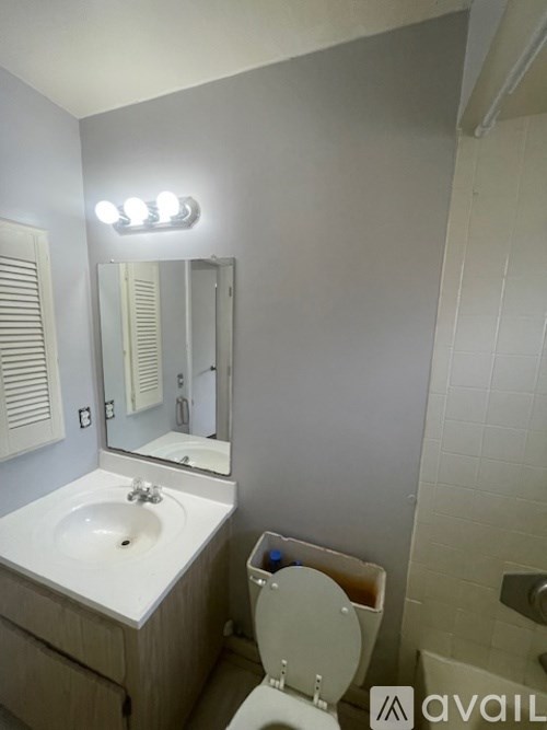 A bathroom with a toilet, sink, mirror, and lights.