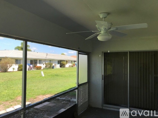 A patio with a fan and sliding glass doors.