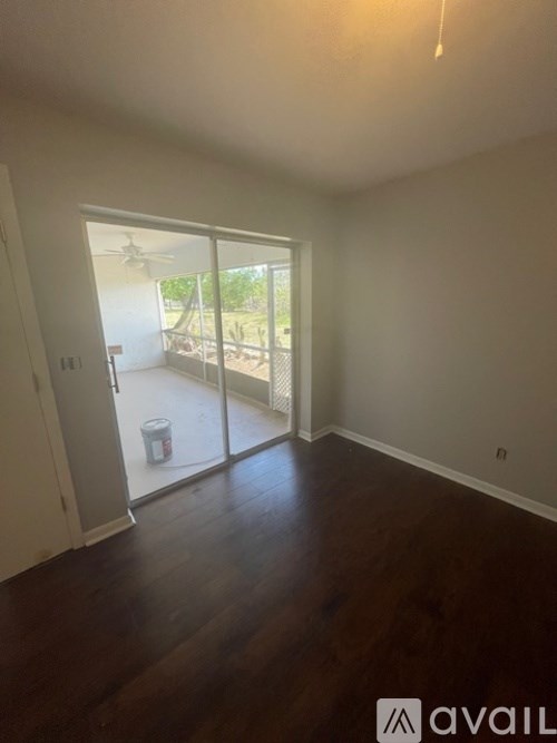 A room with wooden floors and a sliding glass door leading to a balcony.