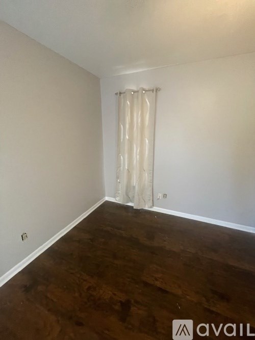 A room with wooden floors and a white curtain.