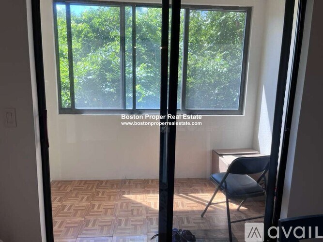 A room with a chair and a window showing greenery outside.
