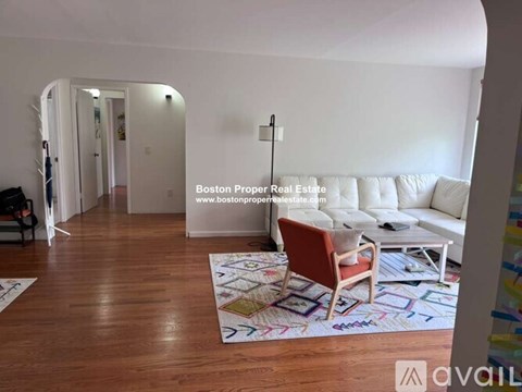 A living room with a white couch and a wooden floor.