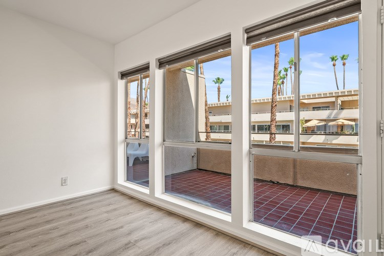 A room with a view of a patio and palm trees.