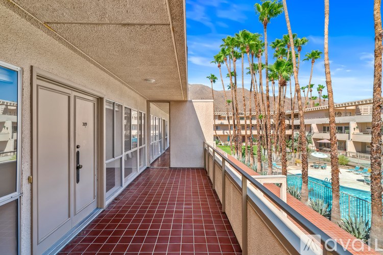 A balcony with red tiles and a pool in the background.