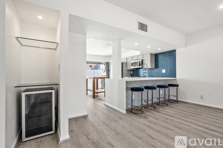 A modern kitchen with a bar stool and a fridge.