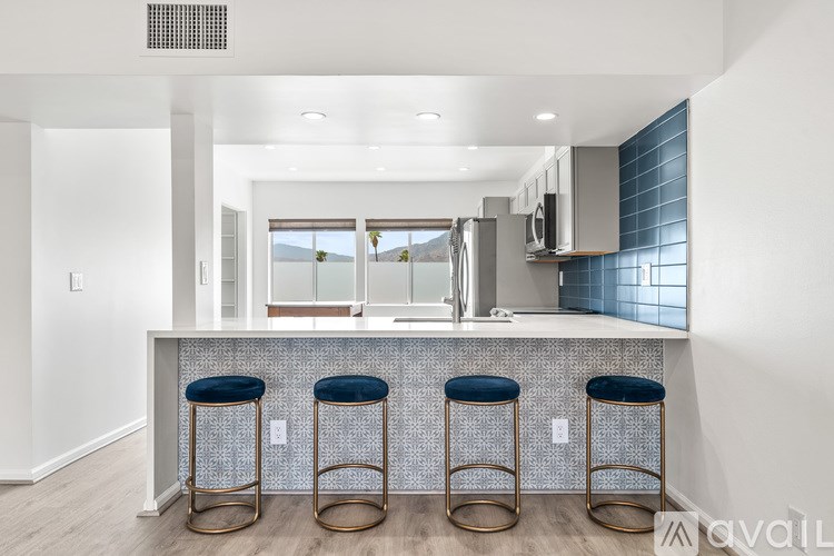 A kitchen with a bar area featuring three bar stools.