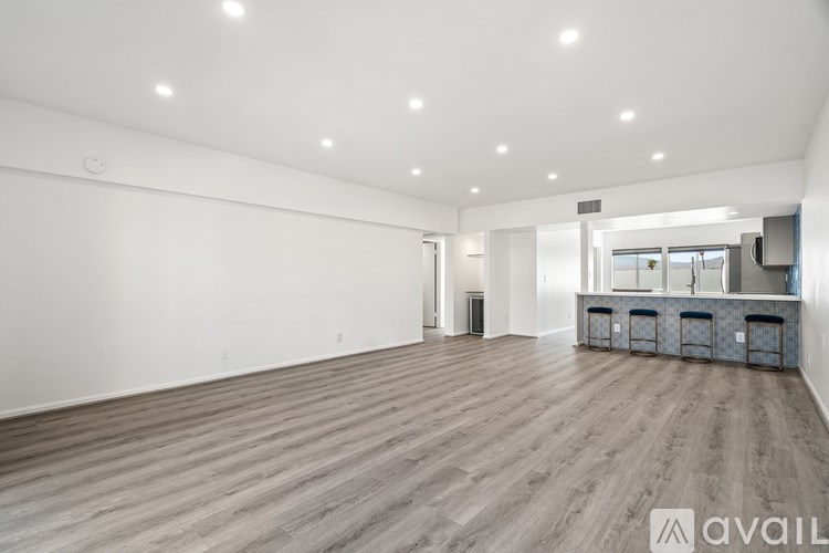 A spacious room with wooden flooring and white walls.