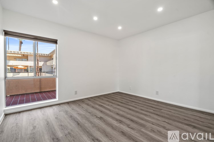 A room with a large window and wooden flooring is available for rent.