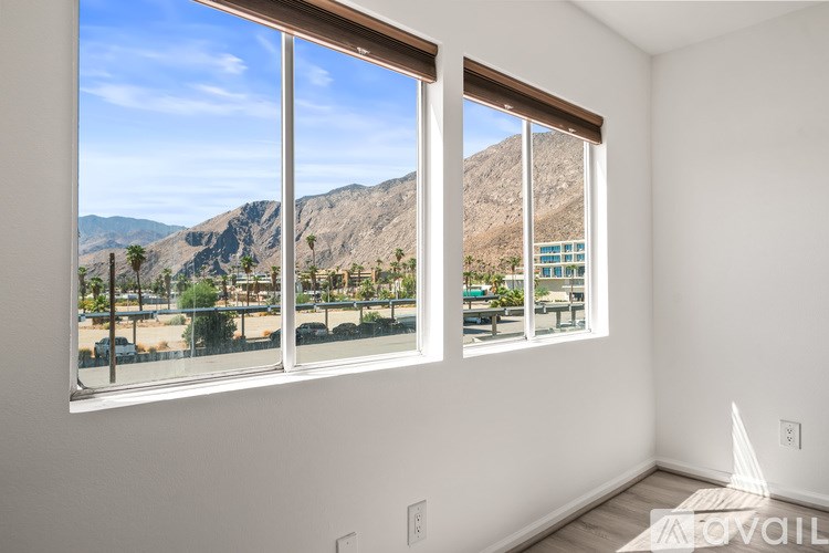 A room with a large window overlooking a mountainous landscape.